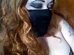 Masked mouth covered with black dildo thrust