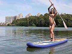 Naked beach shows petite brunette with shaved pussy strolling nude along the shore, her ass on full display in public outdoor fun.