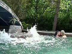 Young lesbian teens casually explore each other's wet pussies while splashing around the sunny swimming pool in a playful outdoor session.