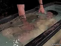 Water bondage session with hogtied slave in distress.