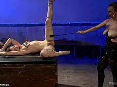 busty dominatrix casually whips her bound lesbian submissive.