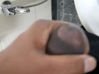 He masturbates his shaved black cock in the restroom until he cums.
