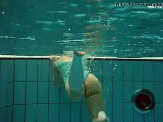 Dasha taucht unter Wasser beim Outdoor-Bad im Bikini als petite Brünette