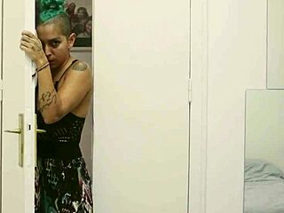 Short tattooed girl with green hair teases in hot striptease, ripping clothes