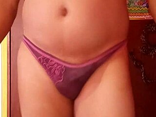 She's casually modeling her wife's panties, slipping in a dildo while lounging in lingerie and nylons.