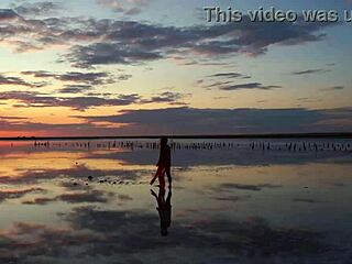 Woman walks along elton salt lake during stunning red sunset