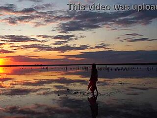 Woman walks along elton salt lake during stunning red sunset
