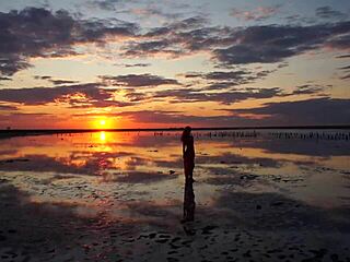 Woman walks along elton salt lake during stunning red sunset