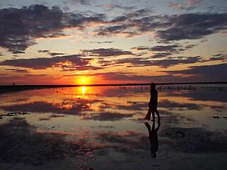 Woman walks along elton salt lake during stunning red sunset