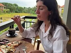 Dívka s cumem v obličeji žere pizzu a polyká na cumwalku v kavárně